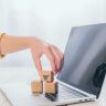 cropped view of woman putting toy paper box on laptop keyboard
