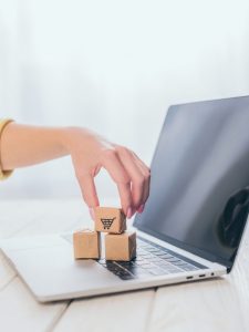 cropped view of woman putting toy paper box on laptop keyboard