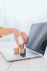 cropped view of woman putting toy paper box on laptop keyboard