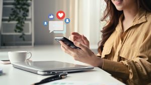 Young woman hands holding and typing on smart phone with notification icons of like, message and comment.