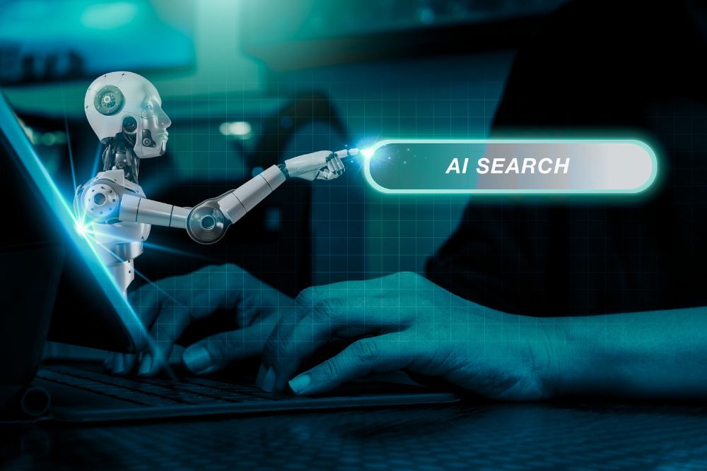Answer Engine Optimization Representação de inteligência artificial em ação: robô tocando uma barra de pesquisa com os dizeres “AI Search”, enquanto uma pessoa digita no teclado ao fundo, simbolizando a integração entre humanos e IA na busca por informações e representando oAnswer Engine Optimization (AEO)