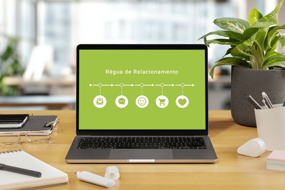 Como criar uma régua de relacionamento Imagem de um notebook sobre uma mesa com a tela exibindo a frase “Régua de Relacionamento” e ícones representando etapas do funil de relacionamento com o cliente. A imagem ilustra o conceito de como criar uma régua de relacionamento eficaz no e-commerce.