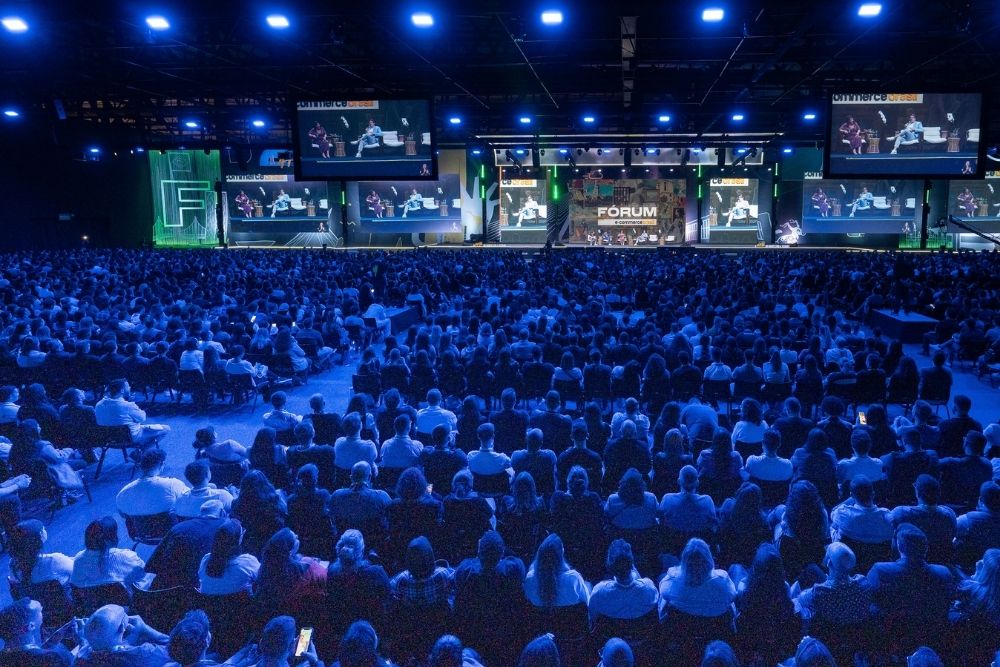 Insights do Fórum E-Commerce Brasil 2025 A imagem mostra uma vasta audiência sentada em cadeiras, voltada para um palco iluminado com telas exibindo apresentações, capturando um momento dos Insights do Fórum E-Commerce Brasil 2025.