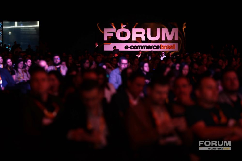 Fórum E-Commerce Brasil 2026 Plateia lotada durante uma edição do Fórum E-Commerce Brasil, com o logo do evento iluminado ao fundo, o maior evento de e-commerce do mundo retorna em 2026 ao Distrito Anhembi, em São Paulo.