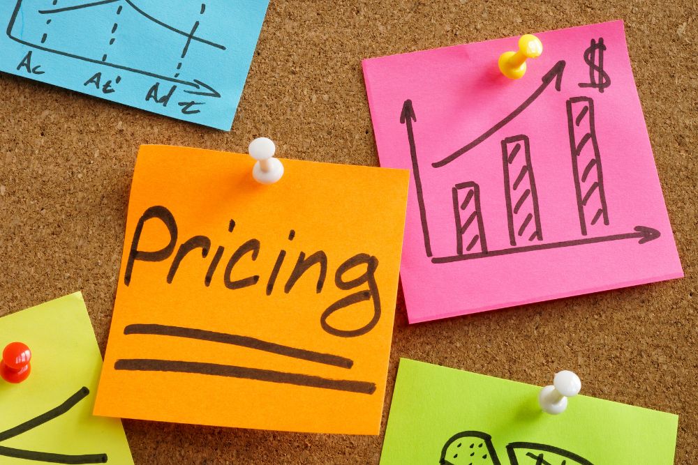 precificação psicológica Post-its coloridos fixados em quadro de cortiça com a palavra "Pricing" em destaque, representando estratégias de precificação psicológica no e-commerce para aumentar conversão e vendas.
