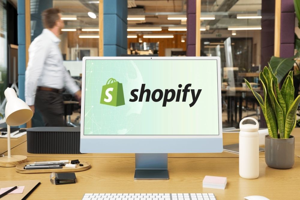 Monitor com a logomarca da Shopify em um escritório moderno, ilustrando os recursos da Shopify em 2026 para e-commerce