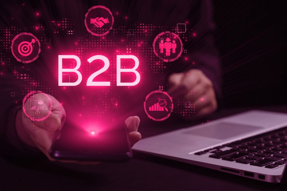 Conceito de VTEX B2B Commerce com a sigla "B2B" em neon e ícones de negócios digitais sobre notebook e smartphone.